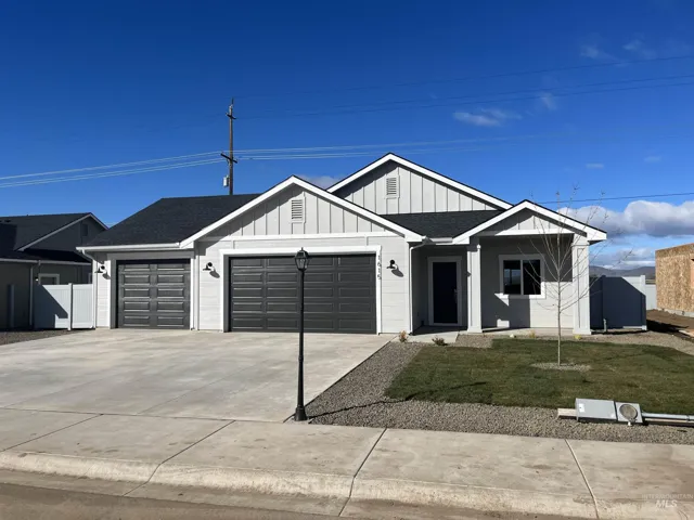View of front of property featuring board and batten siding, a front lawn, driveway, an attached garage, and roof with shingles