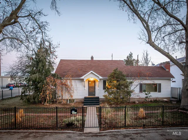 View of front of home with a fenced front yard, a shingled roof, a gate, and a chimney