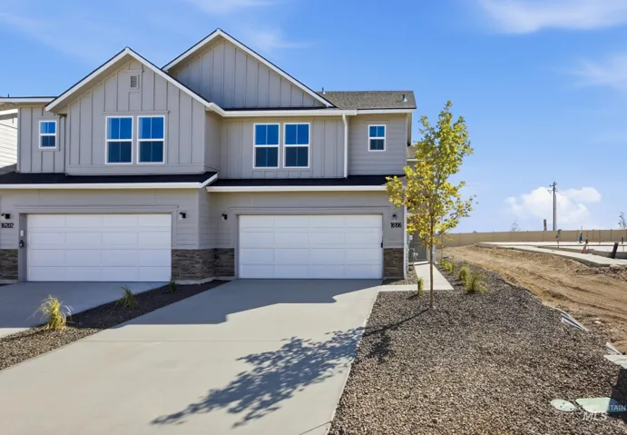 Two-story exterior with board and batten siding, stone facade accents, and white-framed windows