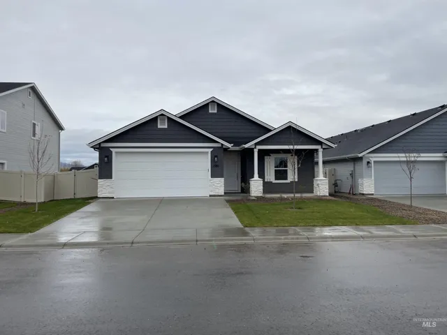 Craftsman inspired home featuring stone siding, driveway, and a garage
