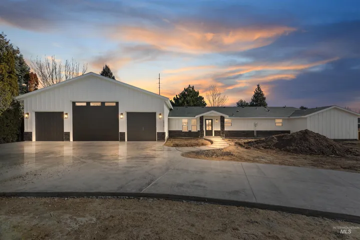 Modern farmhouse-style residence with a three-car garage, board and batten siding, stone facade accents, and a concrete driveway