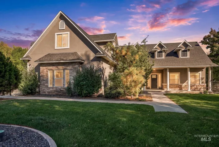 Two-story exterior featuring a stone-veneer facade, multi-gabled roofline, dormer windows, and a covered front porch with classic columns