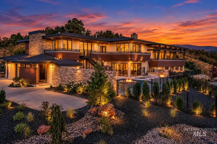Expansive multi-level exterior featuring stone accents, multiple balconies, a paved driveway, and an outdoor patio with fire features