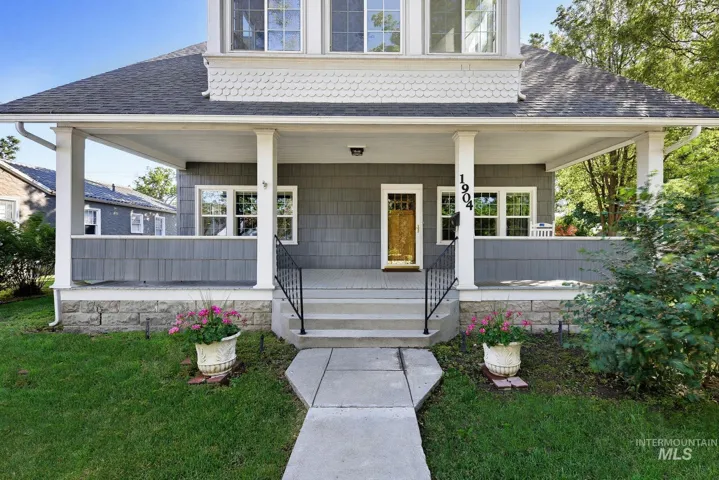 Front exterior showcasing a broad covered porch with white columns, gray shake siding, and a prominent gold-toned front door