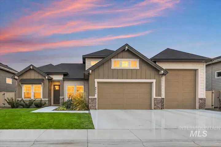 Contemporary residence featuring a two-car garage, board and batten siding, stone accents, and a covered entry