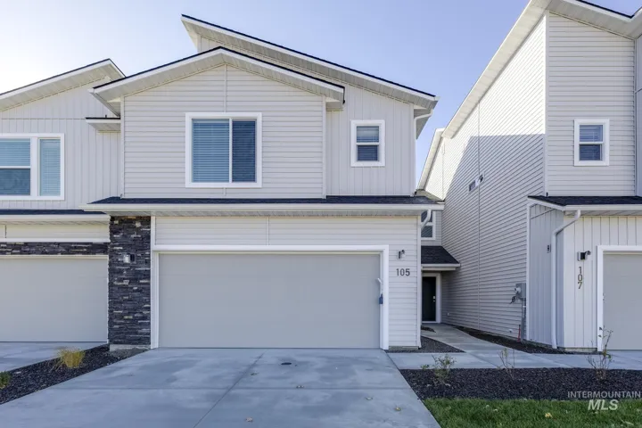 View of front of property with board and batten siding, concrete driveway, a garage, and stone siding