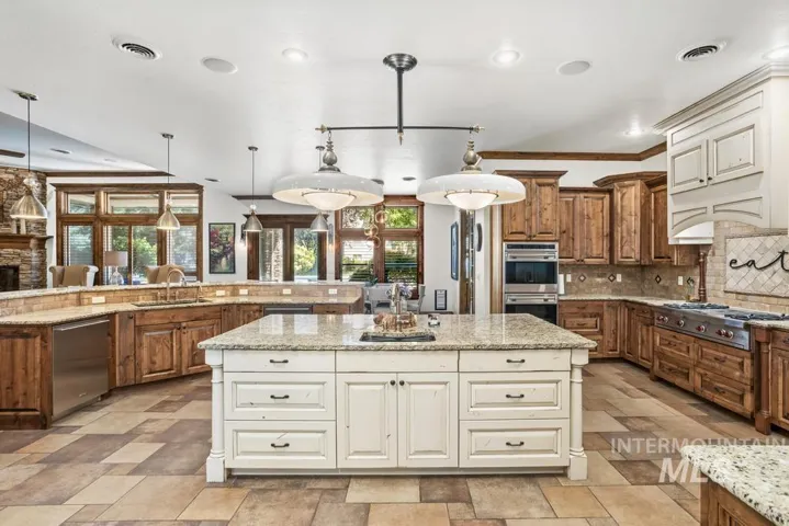 Spacious kitchen featuring a large central island with granite countertop, built-in double ovens, and a professional-grade range