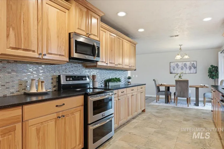 Kitchen featuring appliances with stainless steel finishes, pendant lighting, recessed lighting, tasteful backsplash, and a chandelier
