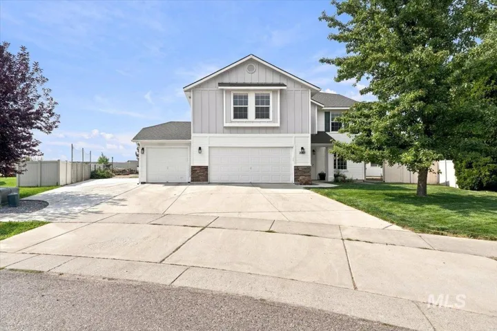 Two-story residence featuring light gray siding, white trim, stone accents, and a dual garage