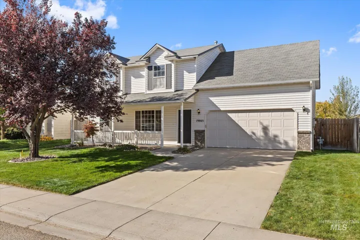 Two-story residence featuring horizontal siding, a gabled roofline, an attached two-car garage, a front porch with railing, and stone exterior accents
