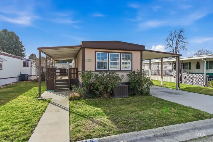 Manufactured / mobile home featuring a front yard, concrete driveway, an attached carport, and covered porch