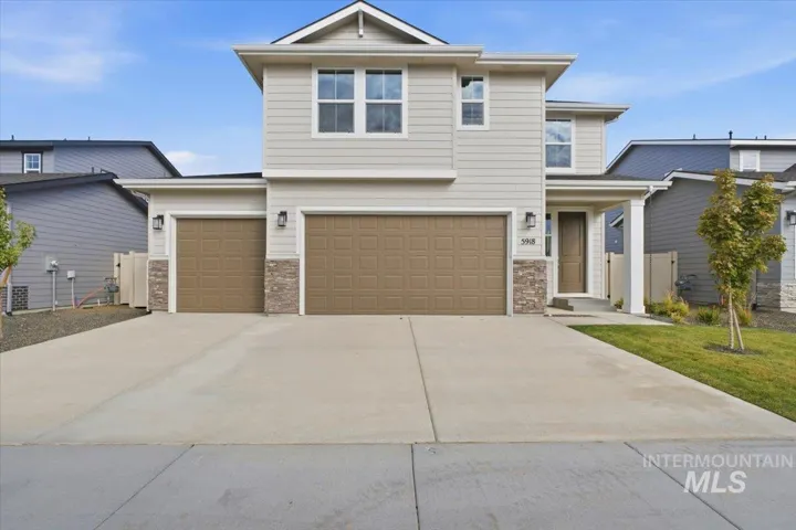 Two-story residence featuring horizontal lap siding, stone veneer accents, a three-car garage, and a concrete driveway