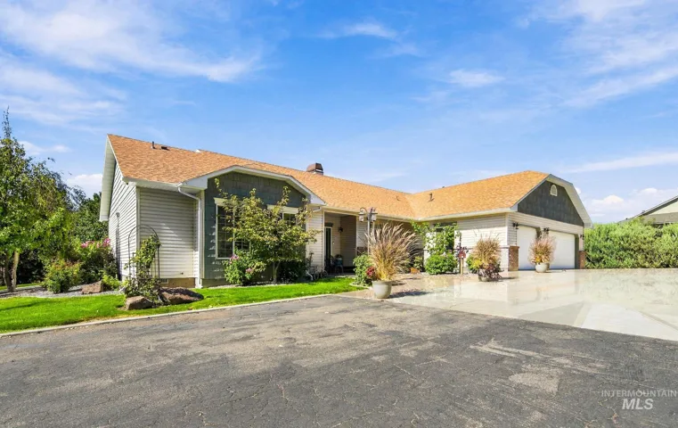 Expansive asphalt driveway leading to a three-car garage