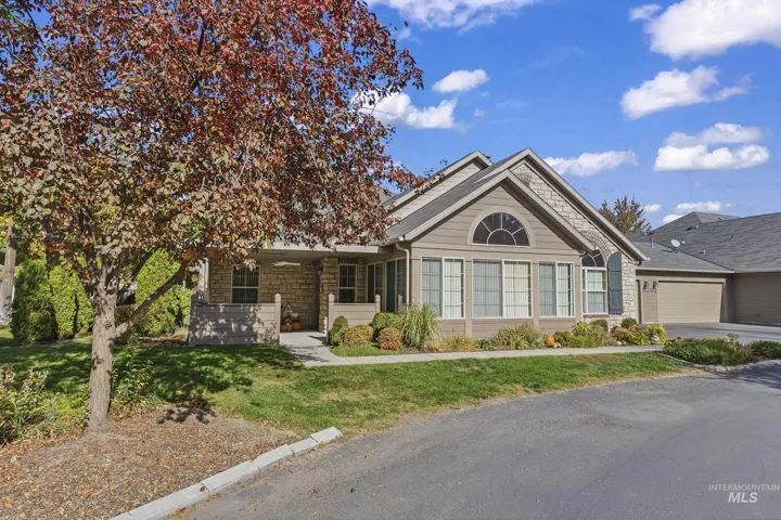 Exterior featuring horizontal lap siding, stone veneer accents, a covered front entry, an arched window, and an attached multi-car garage