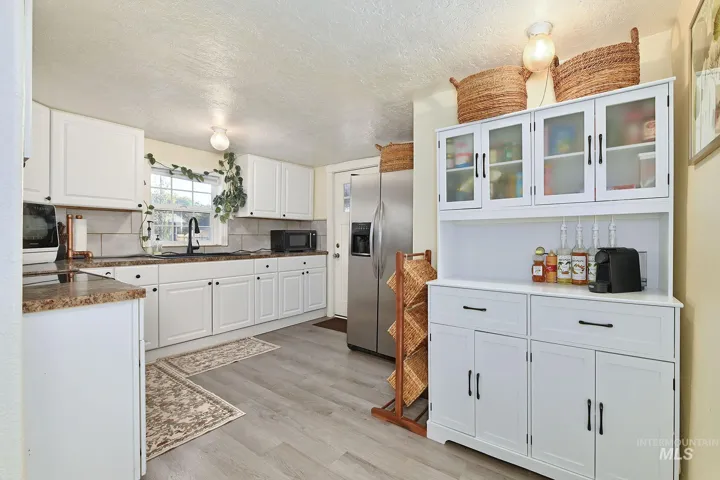 Kitchen featuring white cabinetry, built-in hutch with glass-front upper doors, wood-finish flooring, and stone-finish countertops