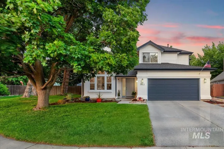 Two-story residence featuring a white facade with dark trim, an attached garage, and a concrete driveway