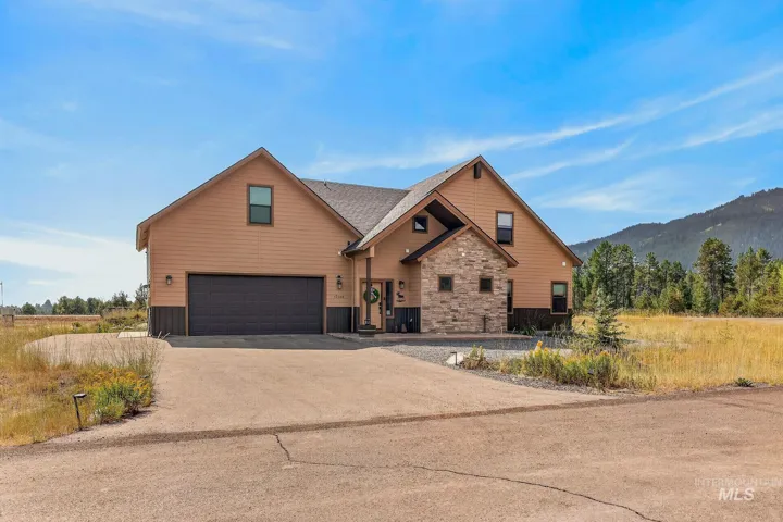 Siding exterior with stone accents, attached two-car garage, and a concrete driveway