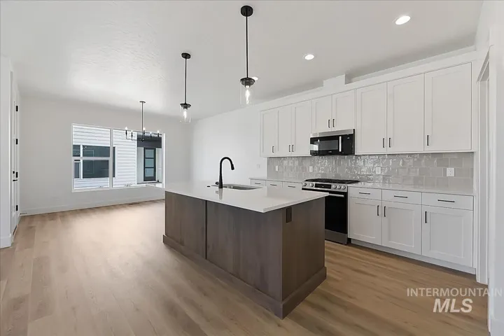 Modern kitchen featuring white shaker cabinetry, stainless steel appliances, and a light gray subway tile backsplash