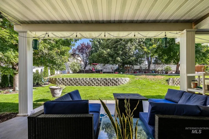 Expansive covered patio with a concrete floor and a large backyard featuring a manicured lawn