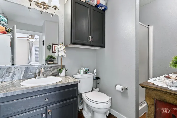 Vanity with an oval undermount sink, a gray patterned countertop, and a matching backsplash