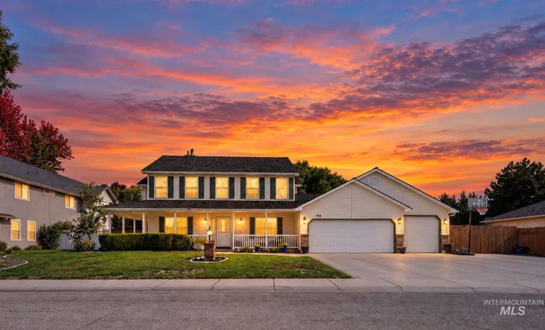 Two-story residence featuring a covered front porch, attached two-car garage, and a wide driveway
