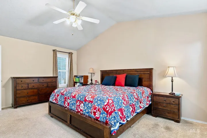 Vaulted ceiling with a ceiling fan, neutral wall paint, and a window with blinds