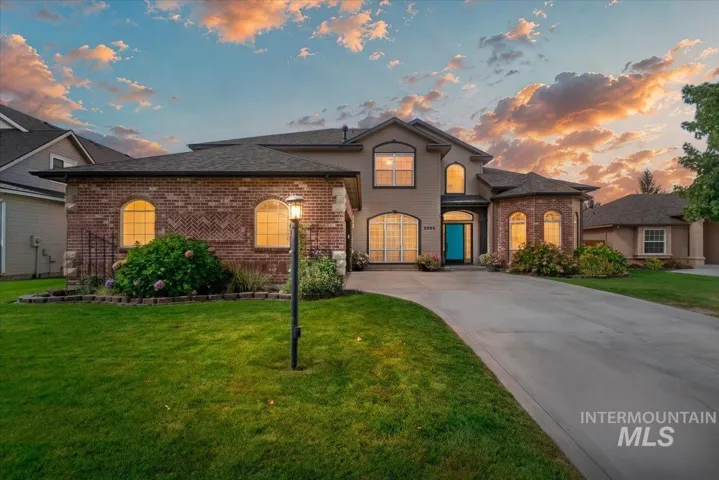 Brick and stucco exterior with arched windows, a vibrant blue entry door, and a spacious concrete driveway