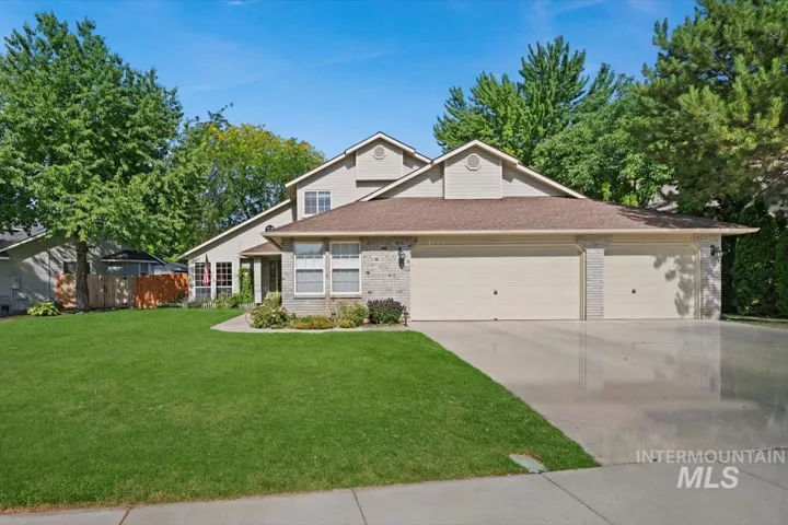 View of front of home with brick siding, an attached garage, driveway, and roof with shingles