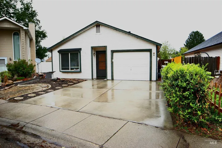 Single-story residence featuring a white siding exterior, attached garage, and a concrete driveway