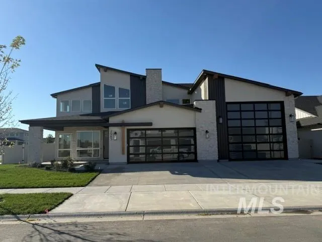 Modern exterior with light-colored stone accents, dark vertical siding, and two glass-paneled garage doors