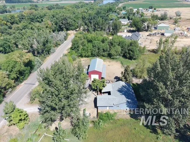 Single-story residence with a gray shingle roof, complemented by a detached red barn with a metal roof