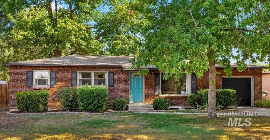 View of front facade with brick siding, a garage, a front lawn, and driveway