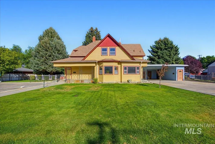 Two-story exterior featuring wood siding, a covered front porch, a bay window, and a detached carport