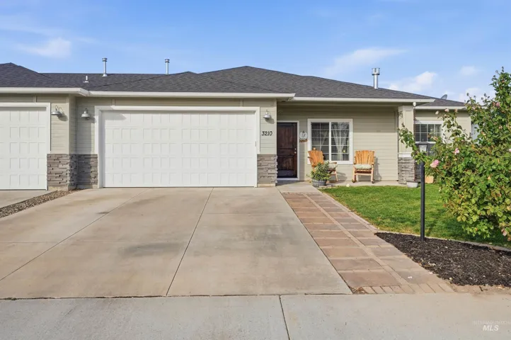 Single-story exterior with light green siding, two-car garage, brick paver pathway, and stone accent facade
