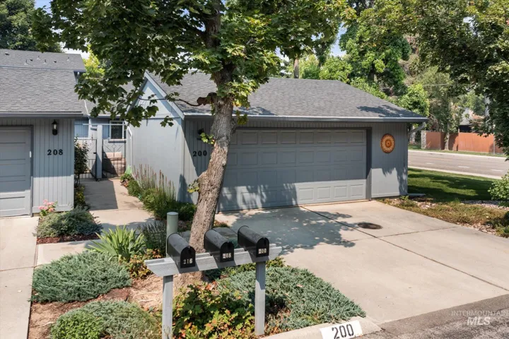 Attached garage, concrete driveway, mature landscaping, sidewalk access, mailboxes