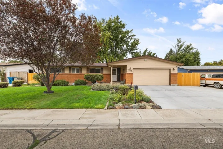 Single-story residence featuring a two-car garage, concrete driveway, brick facade, and mature landscaping