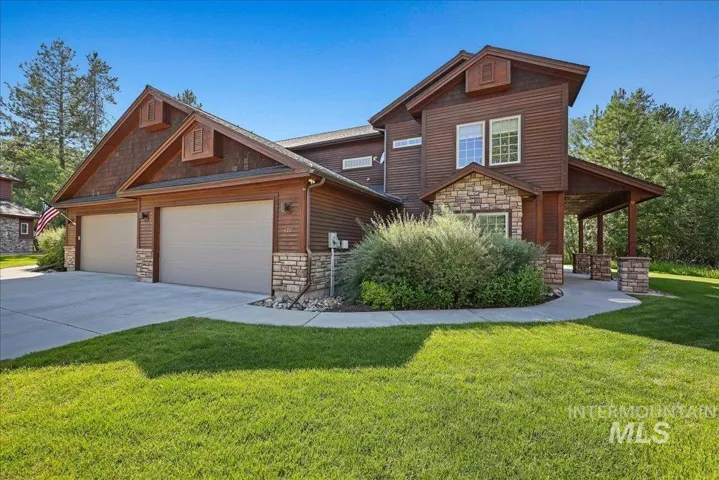 Craftsman-style home featuring stone siding, an attached garage, a front lawn, and concrete driveway