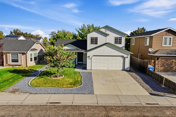 Two-story siding exterior with a two-car garage, concrete driveway, and rock landscaping