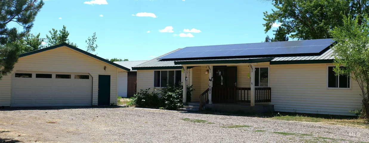 Ranch-style residence featuring light-colored siding, a metal roof with integrated solar panels, and a covered front porch with railings