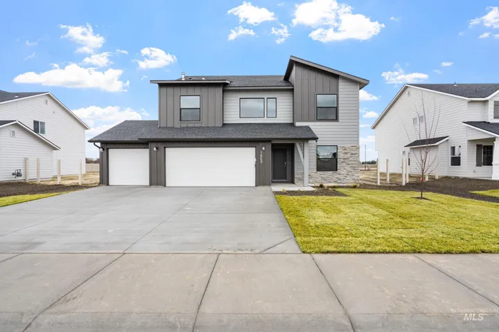 View of front facade with board and batten siding, stone siding, driveway, and a front lawn
