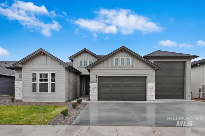 Multi-gabled exterior featuring horizontal lap siding, stone veneer accents, a multi-car garage, and concrete driveway