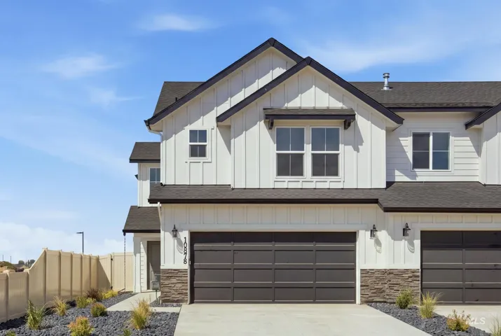 Contemporary exterior featuring board and batten siding, dark shingle roofing, stacked stone accents, and a two-car garage