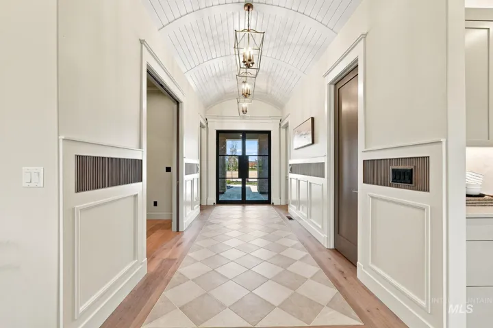 Barrel-vaulted ceiling with wood paneling, decorative wall paneling, tile and wood-finish flooring, and black-framed glass entry door