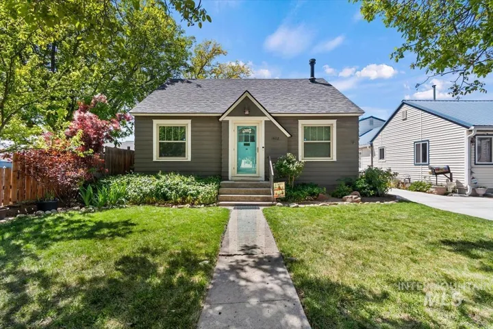 Charming exterior featuring dark gray siding, a striking turquoise front door, and a gray shingle roof