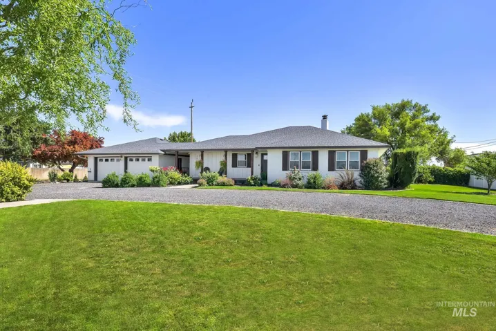 Ranch-style house with an attached garage, a front lawn, a chimney, driveway, and roof with shingles