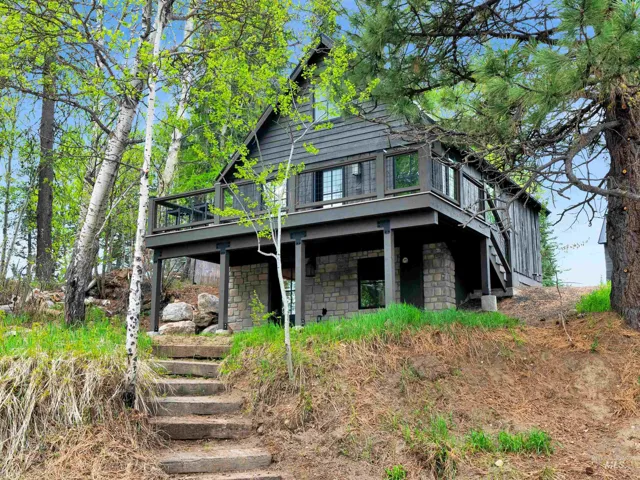 View of front facade with stone siding and a wooden deck