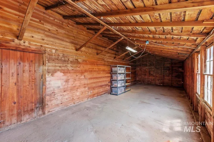 Wooden interior walls, exposed ceiling rafters, concrete flooring, and multiple windows