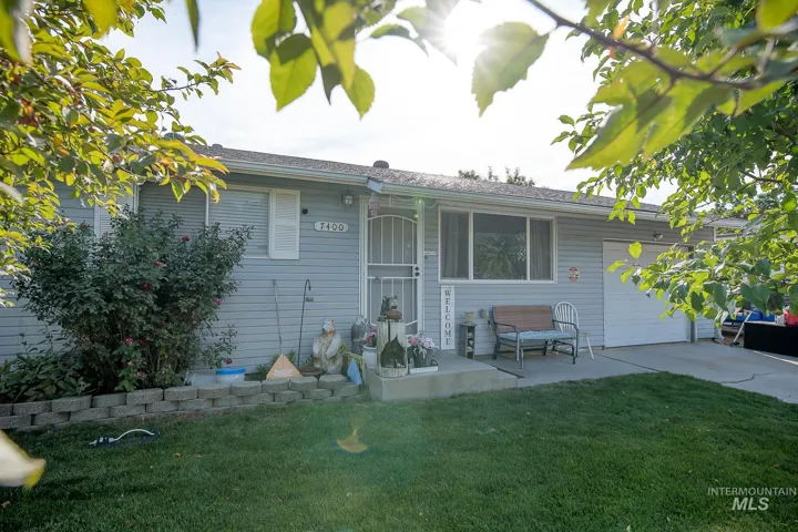 Light blue horizontal siding, white window trim, attached garage with white door, concrete driveway, and front entry porch with concrete steps