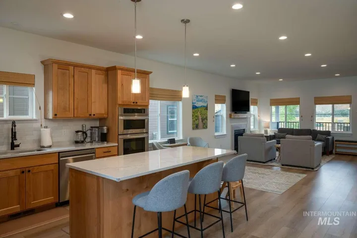 Kitchen island with light-toned countertop, wood-finish cabinetry, stainless steel appliances, and wood-finish flooring