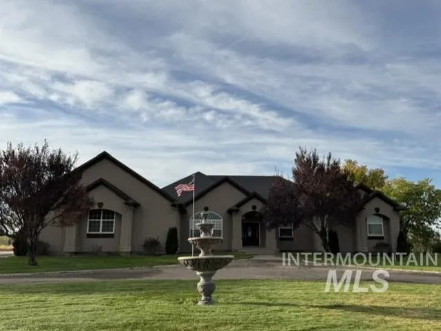 Stucco exterior, dark roof, arched entryways, decorative outdoor fountain, and mature landscaping